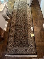 Full length of runner rug laid out on parquet floor showing fringe end.