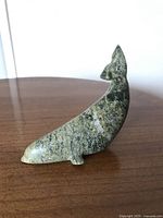 Side profile view of the greenish-gray soapstone whale carving showing the smooth polished surface and overall shape.