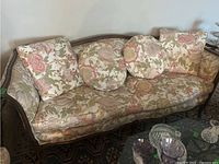 Front view of wood frame sofa with floral cloth upholstery and four cushions arranged on seating area