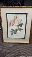 Photo of framed print showing pale pink and white roses with green leaves, ornate gold frame and cream mat