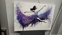 Photo of canvas wall art showing a ballet dancer in mid-leap with a colorful abstract tutu made of purple and blue paint splatters.