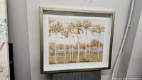 Framed picture of birch trees with white trunks and brownish leaves, light wood frame visible.