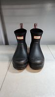 Front view of the black ankle high rain boots showing the Hunter logo on each boot.