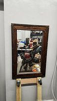 Wooden framed wall mirror with dark brown wood and decorative rivets. Glass cracked lower half in spider web pattern.