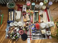 Overview of the lot showing all candles, candle holders, accessories, and decorations on a cloth on the wooden floor.