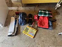 Photo of all items including blankets, jumper cables, red tool case, road maps, brush, sun visor, and cutting knife.