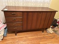 Full front view of the cedar chest showing the three drawers and vertical paneled cabinet door, with brass handles and wooden legs.