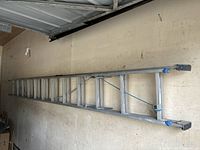 Full view of the extended aluminum ladder to show construction, length, and condition.