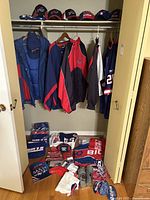 Hats and outerwear hung in closet including baseball caps, knit hats, puffer coat, windbreaker and jerseys