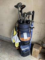 Photo of Spalding golf bag filled with various right handed golf clubs including woods and irons, hanging towels and keychain attached to bag.