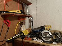 Photo showing various tools including Stanley hand saws, Duramark circular saw, shop light, and hand tools on table