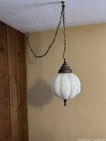Side view of the retro round white glass hanging lamp with chain attached to ceiling hook