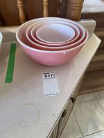 Four pink Pyrex mixing bowls nested on countertop, showing exterior color and nesting