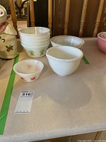 Photo showing multiple retro Pyrex bowls in white milk glass with various green patterns and plain white bowls, including stack of smaller bowls.