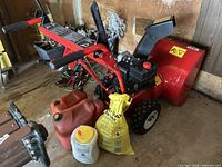 Red MTD Yard Machines single-stage snowblower with 24-inch steel auger housing, black adjustable discharge chute, handlebars with foam grips, mounted on two lugged drive wheels