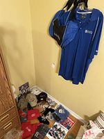Photo showing blue Nike Canadian Open golf shirt hanging on wall, matching blue and black golf bag, and on floor sports cards, caps, and promotional sports memorabilia.
