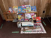Image displaying a wooden shelf with multiple children's books, small toys, a Culligan truck toy, and a small floral area rug underneath
