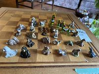 Overview photo showing 26 figurines arranged on a chessboard, highlighting the variety of Wade ceramic and glass figures.