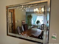 Front view of the rectangular wall mirror showing the clear bevelled glass frame with silver floral pattern and reflective surface.