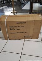 Cardboard box labeling the bike trainer model, quantity and certification mark.