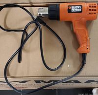Black & Decker heat tool laying on a cardboard box showing the entire tool and cord.