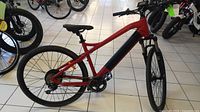 Side profile of red electric bicycle showing frame, battery, wheels and kickstand