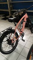 Side angle showing pink frame, saddle, pedals and rear wheel
