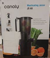 Box of Canoly JE-68 masticating juicer showing the model and features such as big feeding mouth, safety lock & cooling system, low-noise motor, juice and pomace separation.