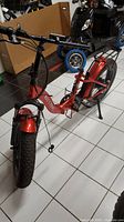 Front view of the red Max S electric bike showing fat tire, handlebar without left brake lever and grip, and missing seat.