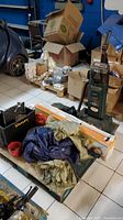 Wide view of lot with black Stanley toolbox, leaf blower, boxed heater, assorted tarps and rags