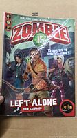Front cover of Zombie 15' Left Alone game showing title, characters and logo