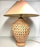 Full view of the lamp showing the coral painted wicker base and large off-white conical lampshade.