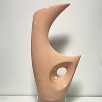 Front view of abstract peach ceramic vase with unique sculptural design and cut-out hole