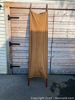 Front view of the WWI stretcher showing full length and canvas surface held by wooden poles.