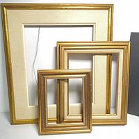 Three gold tone picture frames of varying sizes displayed upright showing front with mats inside.