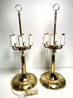 Pair of solid brass candelabra lamps with six faux candle light holders each, cord and base visible, standing upright against a white background.