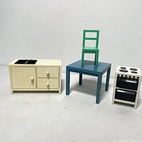 Photo showing cream-colored kitchen cabinet, blue table with green chair on top, and white stove with black burners