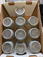 Top-down view of all 10 mason jars inside an open box, showing dusty but intact quart jars with zinc collars.