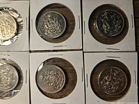 Close-up top view showing six Canadian 50 cent coins in cardboard holders, visible detailed coat of arms design.
