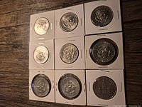 Close-up view of reverse side of three Kennedy Half-Dollar coins showing Presidential Seal and one coin with Liberty Bell and Moon design.
