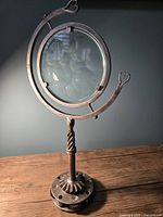 Full view of Alberto Palma magiscope art sculpture showing metal frame and glass lens with heart-shaped accents.