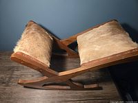 Side view of rocking footstool showing solid wood curved base and horsehair upholstered panels with nailhead trim