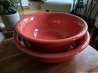 Top-down and side view of the two coral-colored Fiestaware ceramic pieces stacked together on a wooden surface.