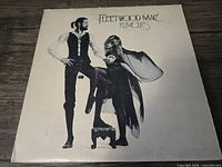 Front cover of Fleetwood Mac Rumours vinyl album featuring two band members posing.