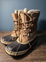 Photo showing pair of beige and black Sorel winter boots with lace-up front and fleece lining inside.