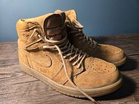 Angled front-quarter view of both shoes on wooden surface against blue background