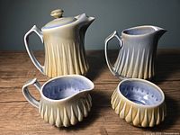 Full view of vintage Wade Irish porcelain tea set: teapot, water pitcher, creamer, and sugar bowl showing vertical fluted pattern and glaze.