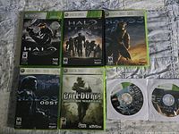 Six Xbox 360 game cases displayed including four Halo titles and one Call of Duty 4, along with two loose discs in paper sleeves.