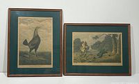 Two framed antique prints displayed side by side against a white background. Left print shows a large bird, right print shows a fishing scene.