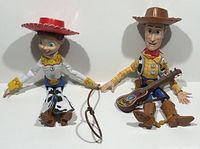 Photo of Woody and Jessie pull string dolls seated holding hands with cowgirl lasso between them.